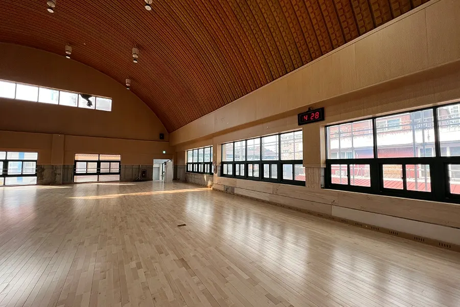 아치형 목재 천장 아래 체육관 전체 전경과 통창 라인